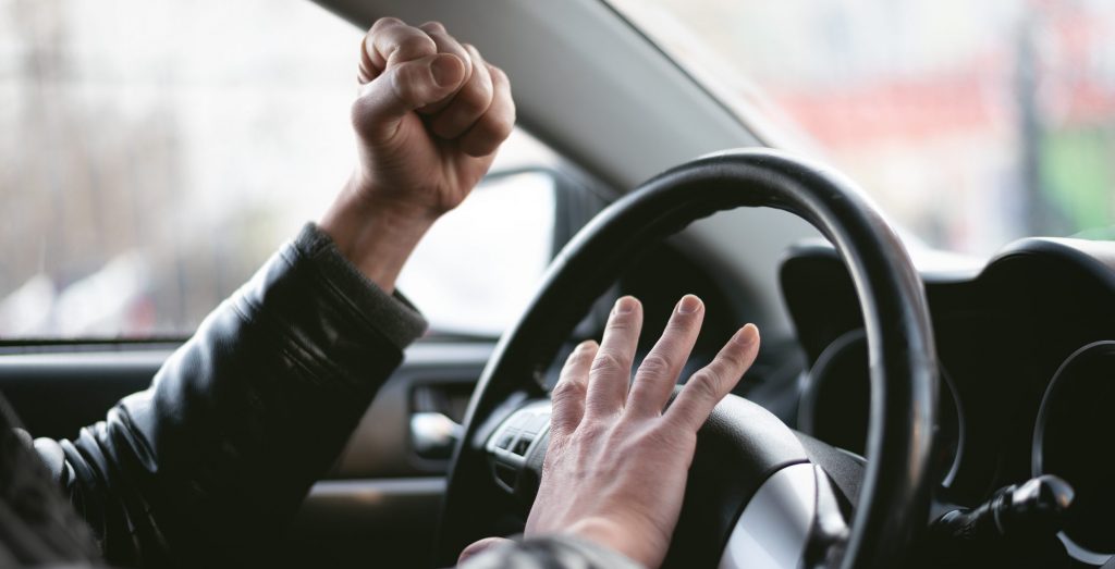 mains d'un conducteur en colère poing gauche serré et main droite sur le volant